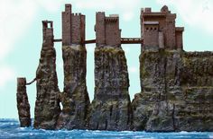 a castle made out of rocks sitting on top of the ocean next to a cliff