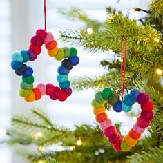 an ornament hanging from a christmas tree decorated with pom - poms