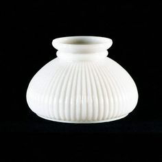 a white vase sitting on top of a black table