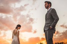 a bride and groom standing in front of the sunset