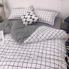 an unmade bed with black and white comforter, pillows and blankets on it