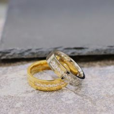 two wedding rings sitting on top of a stone floor next to each other with diamonds in them