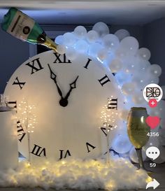 a white clock with champagne being poured into it's glass and surrounded by balloons