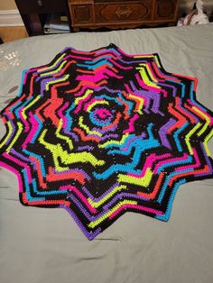 a multicolored crocheted rug on a bed