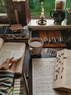 a person sitting at a table with books and coffee cup in front of them, next to a window