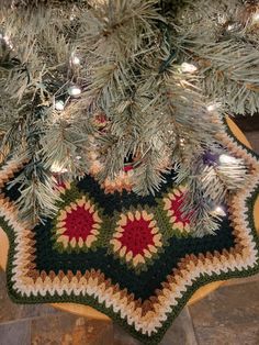 a crocheted christmas tree skirt is hanging from the top of a pine tree