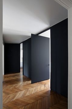 an empty room with black doors and wooden floors