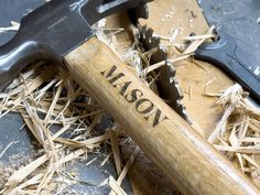 a hammer with the word mason on it next to some wood shavings