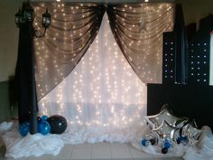 a stage set up for a party with balloons and streamers on the curtained wall