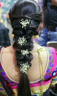 the back of a woman's head with long hair and flowers in her hair