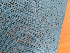 a blue crocheted blanket sitting on top of a wooden table