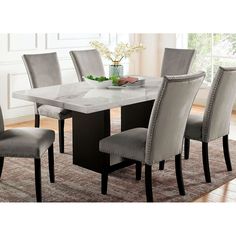 a dining room table with grey chairs around it