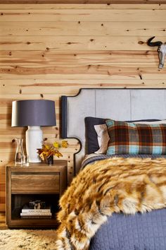 a bed room with a neatly made bed and a cow head on the wall behind it