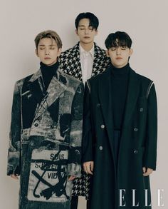 three young men standing next to each other in front of a white wall wearing coats