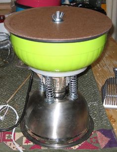 a green and white bowl sitting on top of a metal stand next to a hair dryer