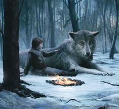 an image of two people sitting in the snow next to a wolf and a campfire