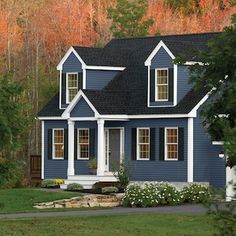 a blue house with white trim on the front and side windows, surrounded by trees