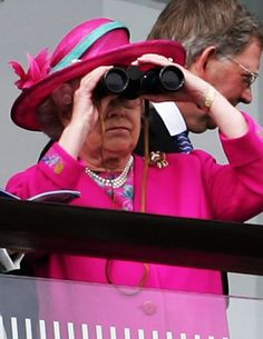 queen elizabeth looks through binoculars as she watches the races