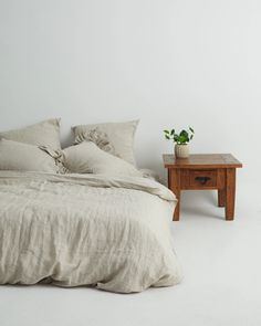 a bed sitting next to a wooden table with a potted plant on top of it