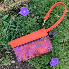 "Delicious Orange Leather combined with a hot,Orange Purple Batik..Those colors together end up looking a lot like Fall in the Finger Lakes! It's a minimalist Handbag,Wristlet, Clutch, Wallet ,or Phone Case. Top zip opens to roomy interior that will fit the largest Phone and a small pocket for your credit cards. AND there's a clip off key ring! Outside features one large zip pocket. 7.5\" wide 4.75\" deep 1.25 bottom" Orange Pouch Wallet For Daily Use, Orange Rectangular Coin Purse For Daily Use, Orange Pouch Wallet For Everyday Use, Orange Rectangular Bag With Zipper Pouch, Rectangular Orange Bag With Zipper Pouch, Orange Pouch Shoulder Bag With Cell Phone Pocket, Orange Bags With Cell Phone Pocket For Daily Use, Orange Clutch Bag For Everyday Use, Orange Clutch For Everyday Use