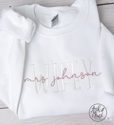 "This Wifey Sweatshirt is the perfect gift for any bride. This super soft sweatshirt is embroidered with the bride's last name on the front, making it a special, one-of-a-kind wedding gift. It's sure to make her feel like a Wifey! SWEATSHIRT DETAILS: - Bella & Canvas Unisex drop shoulder sweatshirt. - Combed & ringspun cotton/polyester. - Lightweight sweatshirt that is perfect to wear year round. - Thread colors:  White for WIFEY wording, Rose Gold for overlapping wording (Example: Mrs. \"last name\"). HOW TO ORDER: - Select your size from the drop down menu - For personalized items add your personalization to the \"Add your personalization\" field. - Add to cart - Select your shipping from the drop down menu. - Enter any additional information in the \"notes to seller\" field ★ If you are Long Sleeve Cotton Sweatshirt For Anniversary, Embroidered White Sweatshirt For Gift, White Sweatshirt With Letter Embroidery As Gift, Wifey Shirt, Bride Wedding Gift, Wifey Sweatshirt, Bride Sweatshirt, Drop Shoulder Sweatshirt, Sweatshirt Details