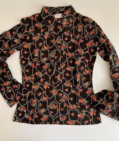 "1960'S MOD Blouse in a novelty print of flower baskets. This is 100% combed cotton. There are huge butterfly lapels that are 4-1/2 inches long. This top is nipped at the waist and flares a bit at the hip. This is in EXCELLENT VINTAGE CONDITION. This garment has never been worn, and is considered NOS - New-Old Vintage Dead-Stock. The LABEL READS: \"TGL\" Stockholm European size 40 (the great britain & usa sizes are not listed correctly) DROP DRY ( lol.. which I think they meant DRIP DRY ) Je Vintage Black Top With Retro Print, Vintage Fitted Printed Tops, Fitted Vintage Printed Tops, Vintage Patterned Blouse With Floral Print, Vintage Floral Print Patterned Blouse, Vintage Style Patterned Blouse With Floral Print, Patterned Floral Print Vintage Blouse, Retro Cotton Blouse With Retro Print, Fitted Vintage Blouse With Vintage Pattern