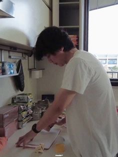 a man standing in front of a counter cutting up food on top of a table