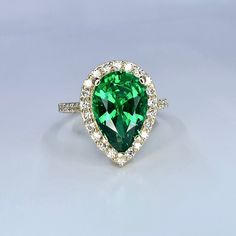 a pear shaped green diamond ring with diamonds around it