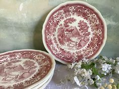 two red and white plates sitting next to each other on top of a table with flowers