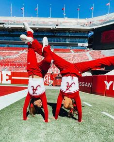 two cheerleaders doing handstand on the field