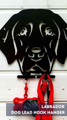 a dog leash hook hanging on the side of a white door with a red leash attached to it