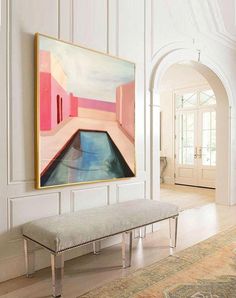 a painting hanging on the wall above a bench in a room with white walls and wood flooring