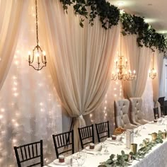 a long table is set up with white linens and greenery on the walls