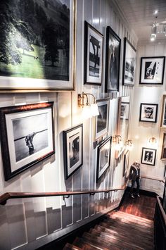 a staircase with pictures on the wall and framed photographs hanging up against the wall behind it