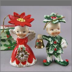 two christmas figurines are standing next to each other with bells in their hands