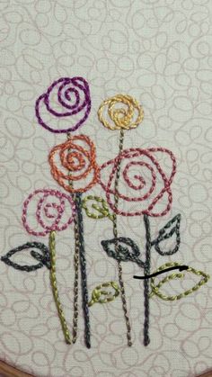 a close up of a embroidery on a piece of cloth with flowers in the middle