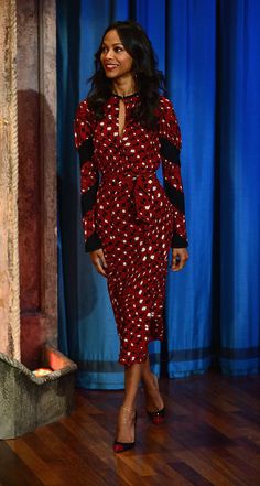 a woman in a red polka dot dress standing next to a blue curtain on the tonight show