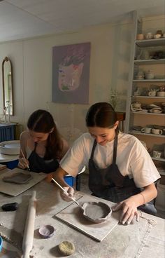 two women in aprons working on pottery