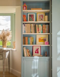 a bookshelf filled with lots of books next to a window