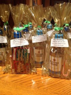 four bottles of beer wrapped in plastic bags on a wooden table with green ribbon around them