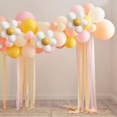 balloons and streamers are arranged on the floor in front of a wall with flowers