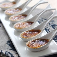 five spoons are lined up on a plate with some food in the middle one is filled with jelly