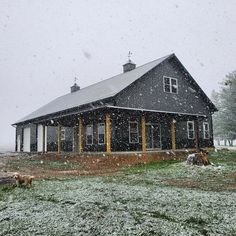 a black house with snow falling on the ground