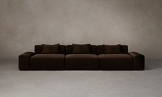 a brown couch sitting on top of a white floor next to a gray wall in front of it