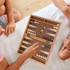 two people sitting on a bed playing backgamula