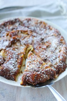 a cake with powdered sugar on top is cut into slices and served on a white plate