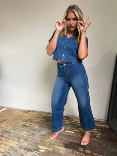 Rock a relaxed look in this dreamy denim duo! Boastin' a rapel collar, short sleeve jacket, button close, and back belt, this blue washed denim top is totally off the hook. Meanwhile, wide leg, ankle length pants are sure to have all eyes on ya! 75.6% Cotton 15% Viscose 9.4% Polyester. Model is 5'7" and wearing a size Medium. Cropped Denim Blue Top With Button Closure, Medium Wash Button-up Denim Top With Buttoned Pockets, Medium Wash Button-up Denim Top, Denim Blue Button-up Tencel Tops, Medium Wash Distressed Button-up Denim Top, Short Sleeve Jacket, Off The Hook, Ankle Length Pants, Sleeve Jacket