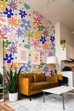 a living room with colorful flowers painted on the wall and a couch in front of it