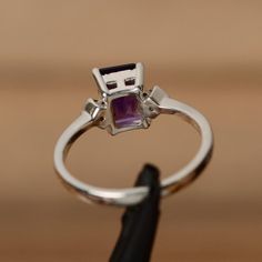 It is a natural amethyst  ring. The main stone is 6mm*8mm emerald cut amethyst, weight about 1.55 carats.The basic metal is sterling silver and plated with rhodium.To change the metal to a solid gold (white/rose) or platinum is also available, please ask for a quotation if you want.You can also go to my shop Home for more elegant rings: https://www.etsy.com/shop/godjewelry?ref=hdr_shop_menuAmethyst is the birthstone of January. More amethyst rings:https://www.etsy.com/shop/godjewelry?ref=hdr_sho Emerald Cut Amethyst Ring For Formal Occasions, Dainty Emerald Cut Gemstone Ring, Emerald Cut Birthstone Jewelry For Promise, Elegant Emerald Cut Amethyst Ring, Elegant Emerald Cut Amethyst Promise Ring, Sapphire Ring With Rectangular Stone And Prong Setting, Purple Gemstone Rings With Baguette Cut, Purple Gemstone Baguette Cut Rings, Purple Baguette Cut Gemstone Rings