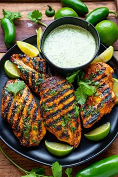 grilled chicken with salsa and limes on a black plate next to sliced jalapenos